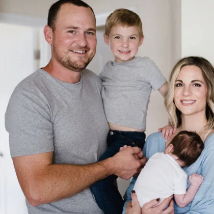 Tyler Sherman holding his son Brooks, standing beside his wife Sarah, who holds their newborn son Maverick